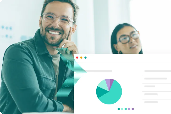A man with glasses is smiling and looking at a computer screen.