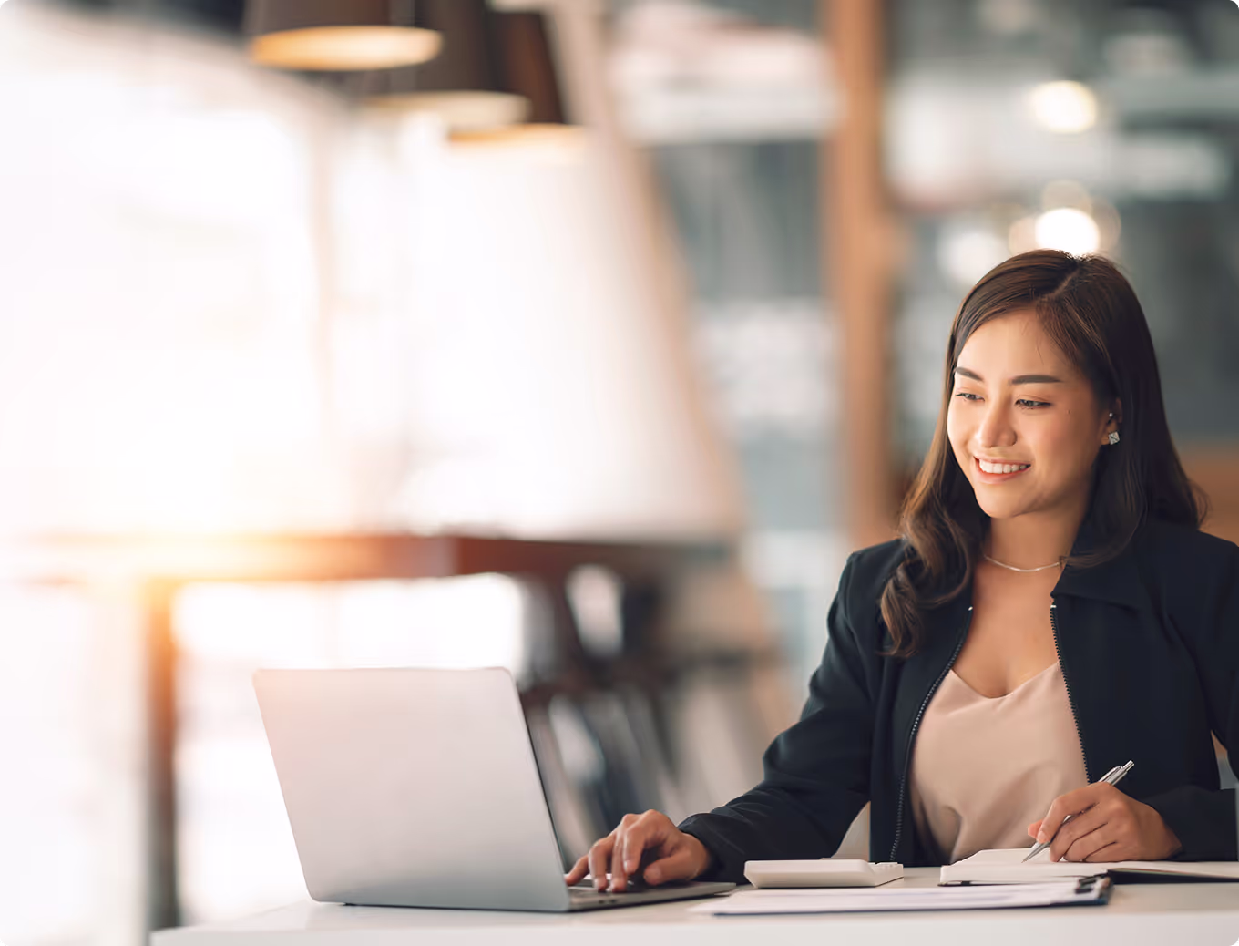 A woman in a black suit is using a laptop.