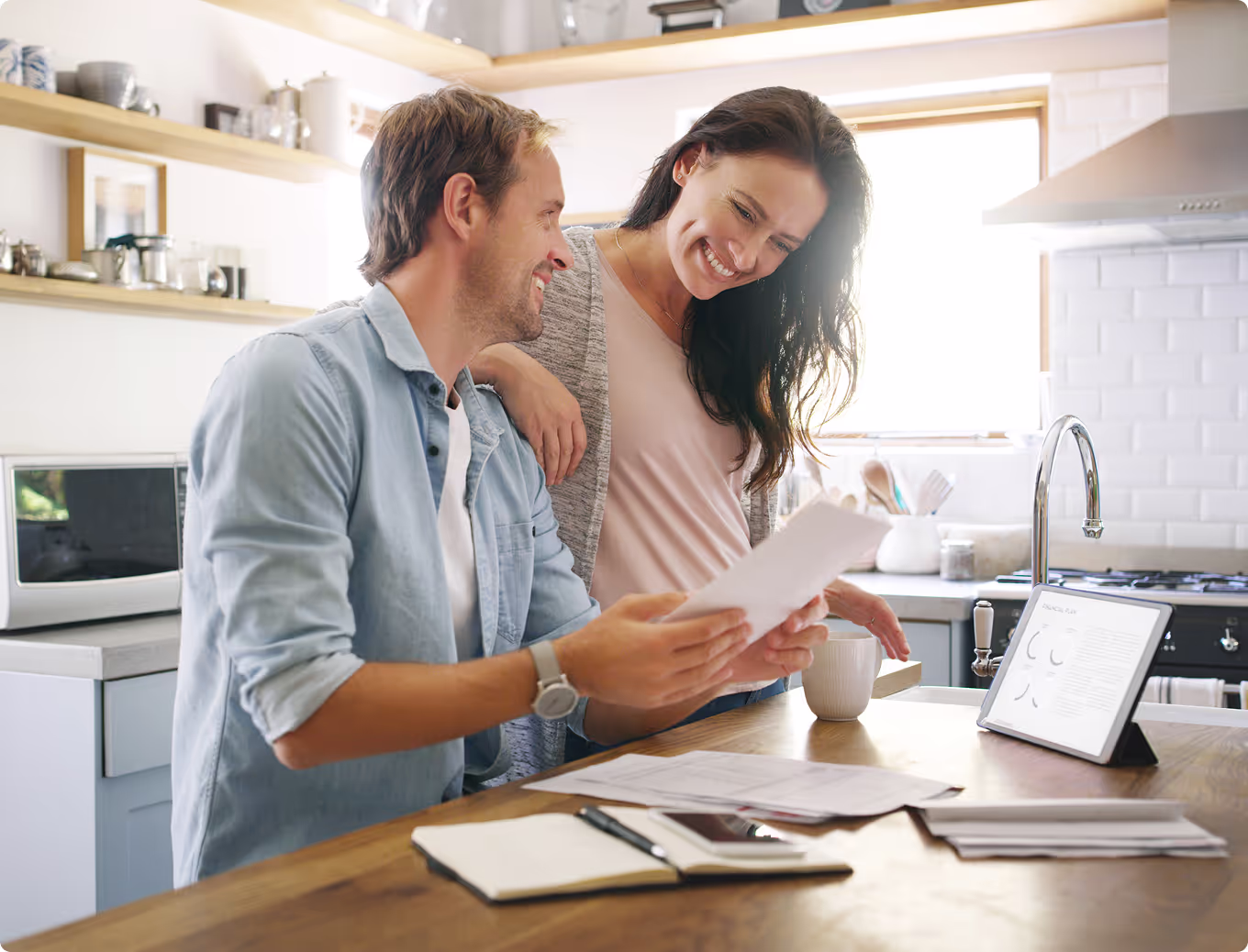 A man and woman are sitting at a table with a laptop and papers.