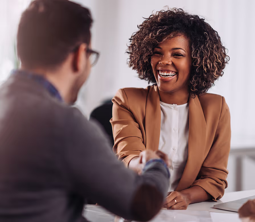 A woman smiling and shaking hands with a man.