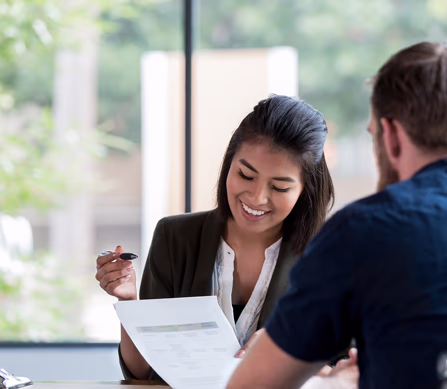 A woman smiling while holding a pen and paper.