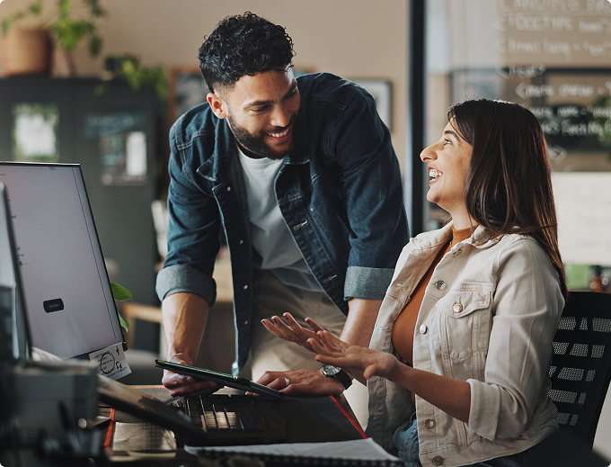 A man and woman are standing in a kitchen, smiling and holding a piece of paper.
