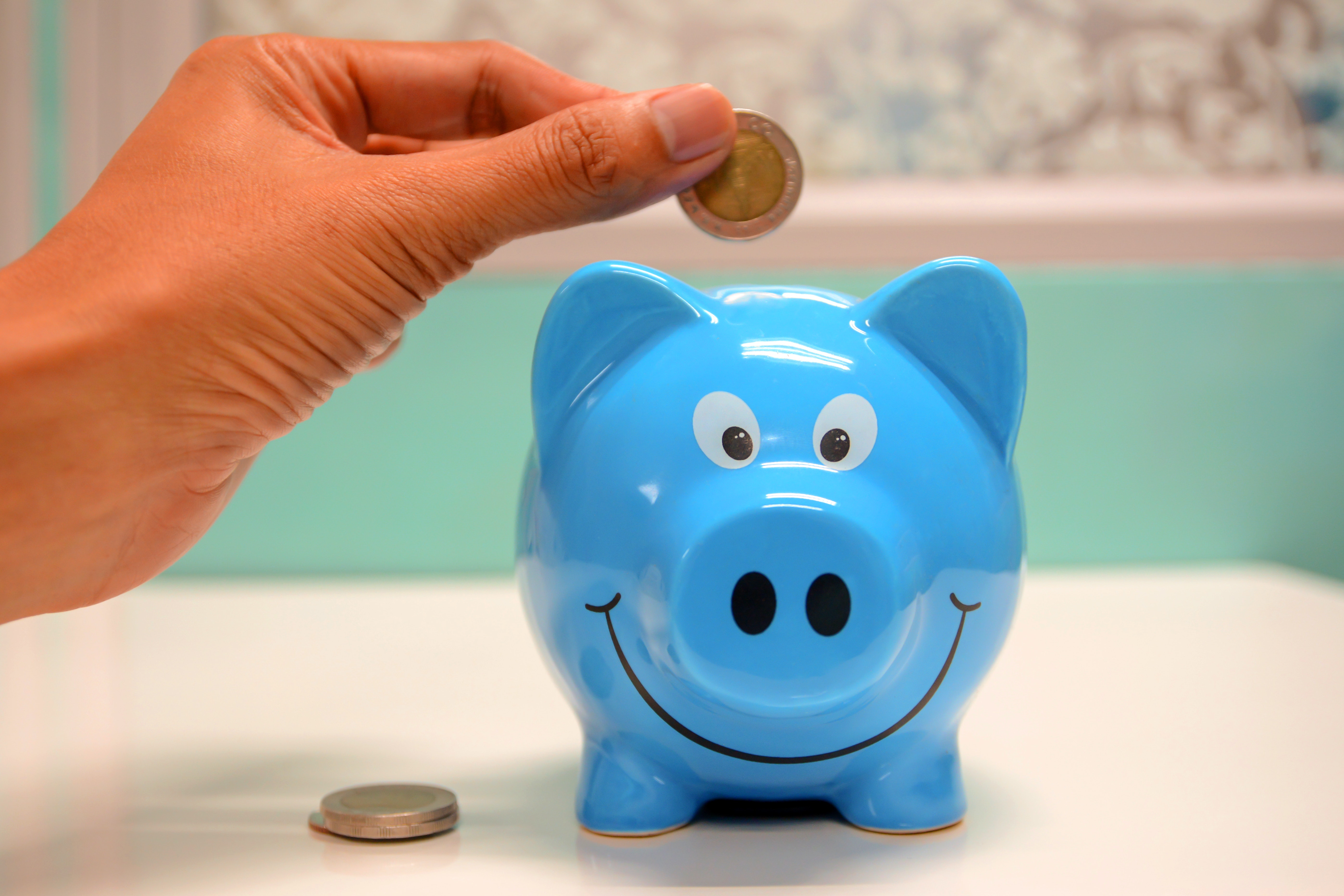 Practicing financial literacy by putting coins in a piggy bank